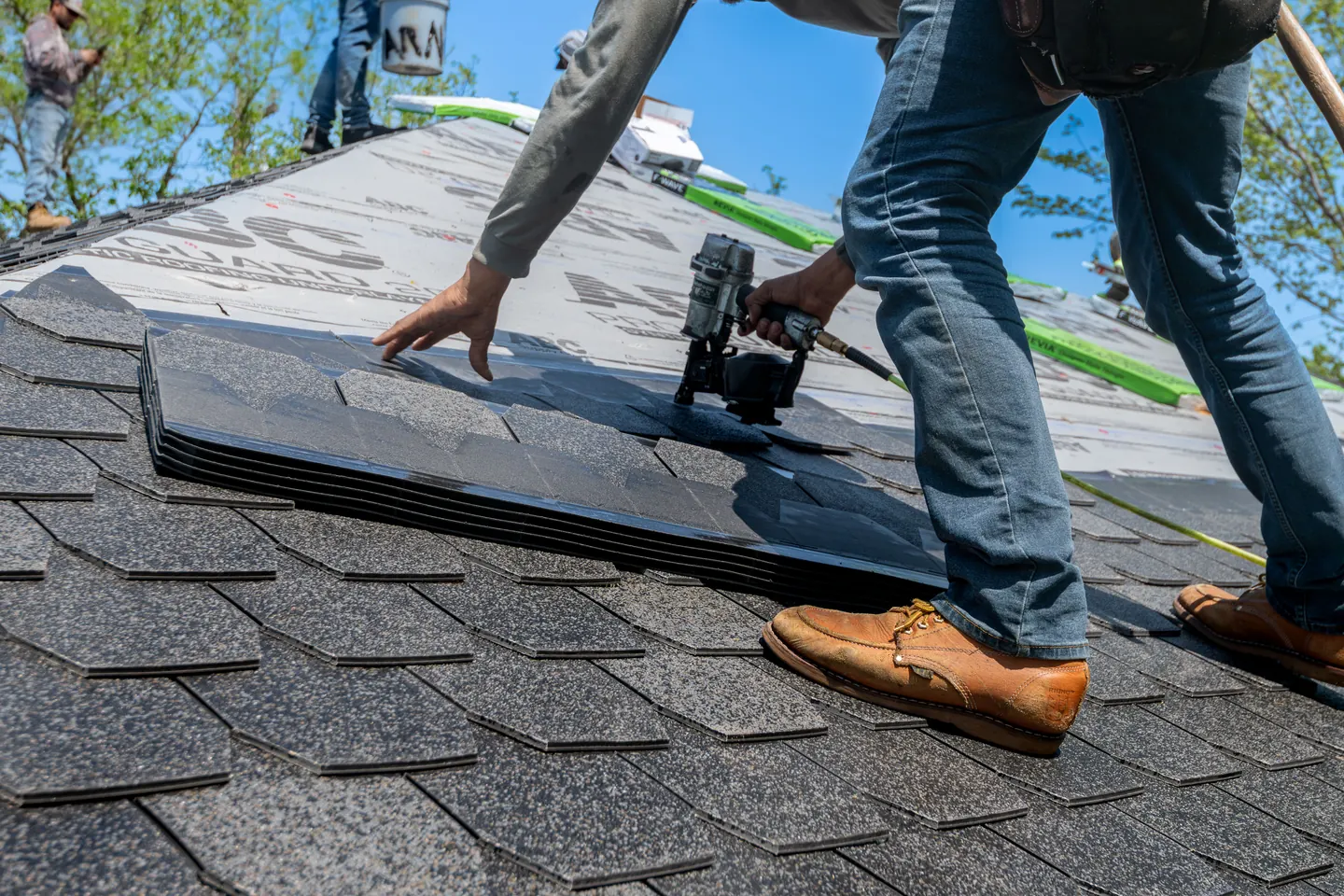 Asphalt shingles being positioned and fastened on a residential roof